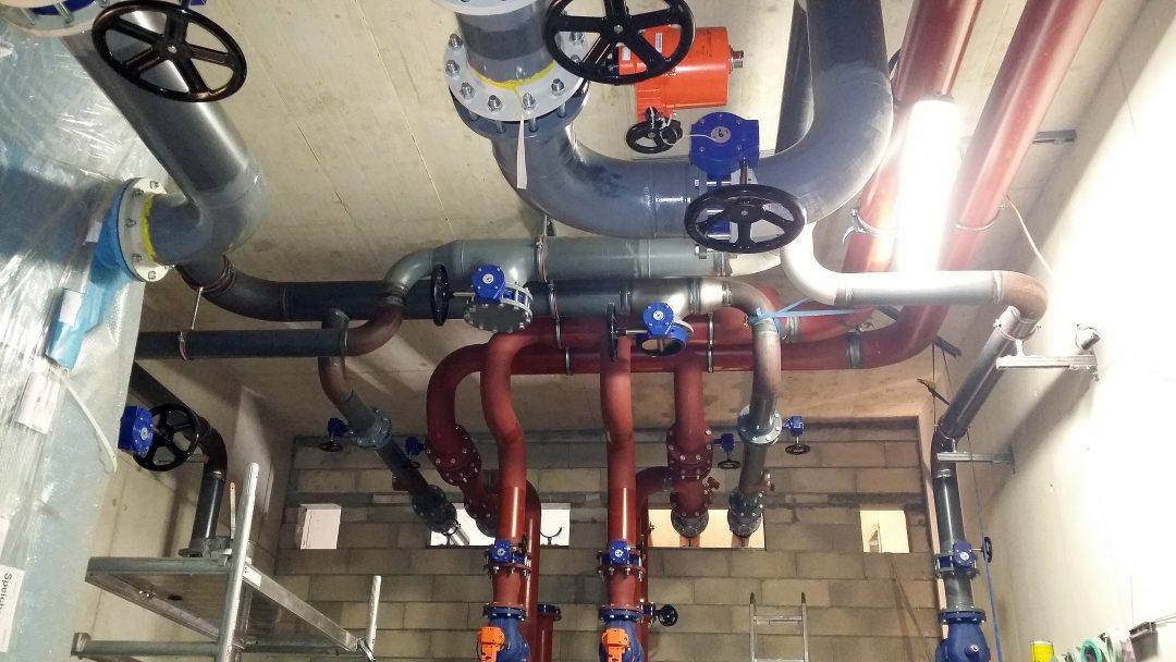 Tuyauteries rouges et grises suspendues au plafond d'une salle technique